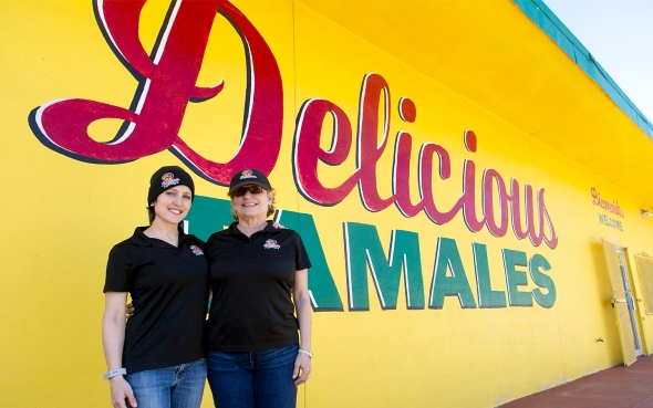 two woman in front of the Delicious Tamales building
